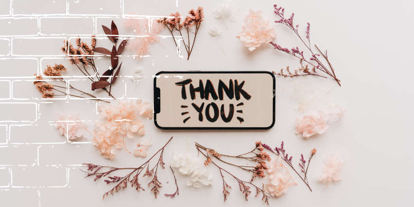 un celular con la palabra gracias en el centro, rodeado de flores