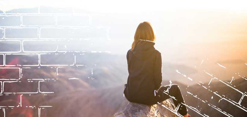 una mujer sentada en un peñon, mirando el horizonte